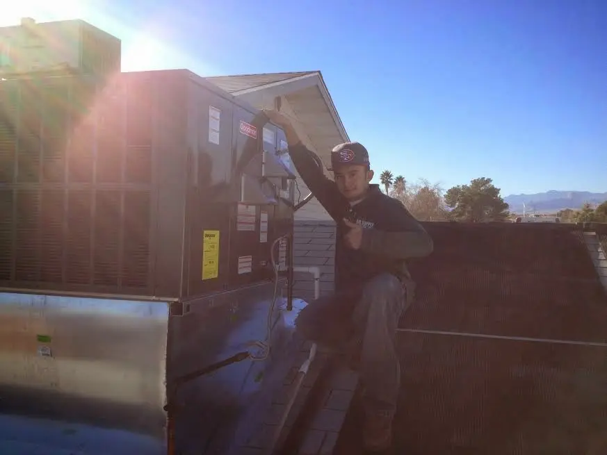 HVAC technician performing Air Duct Repair on a rooftop unit in Bear